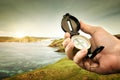 Compass in hand traveler on coastline near ocean on background h