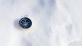 Compass lying on the icy snow in the cold mountain. Orientation and navigation tool for survival adventure equipment and