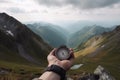 Compass and map in hands of traveler for checking and searching position and direction at the top of peak of mountain while hiking Royalty Free Stock Photo