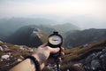 Compass and map in hands of traveler for checking and searching position and direction at the top of peak of mountain while hiking Royalty Free Stock Photo