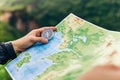 Compass and map in hands of traveler for checking and searching position and direction at the top of peak of mountain while hiking Royalty Free Stock Photo