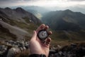 Compass and map in hands of traveler for checking and searching position and direction at the top of peak of mountain while hiking Royalty Free Stock Photo