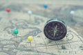 Compass and marking pins on blur vintage map, journey concept Royalty Free Stock Photo