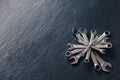 Compass of metal shiny wrenches on textured dark blue stone background. Royalty Free Stock Photo