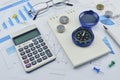 Compass, pen and coin on notebook, accounting background