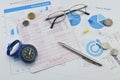 Compass, pen, glasses and coin on saving book, accounting background Royalty Free Stock Photo