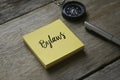 Compass,pen and yellow sticky notes written with Bylaws on wooden background