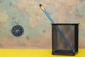 Compass and pencil in a metal pot on a blurred background of an old world map Royalty Free Stock Photo