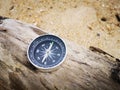 A compass showing the direction point to north on an old tree that washed up during the low tide.,