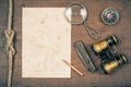 Compass, vintage binoculars, paper, old pocket knife, pencil, magnifying glass on wooden background