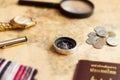 Compass on vintage world map with coins, pen, wrist watch, plane and flag for vacation and travel concept Royalty Free Stock Photo