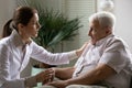 Confident young woman doctor gp consoling worried retired sick man