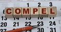 COMPEL - word on wooden cubes on the background of the calendar and pen