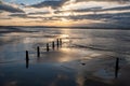 Row of Poles on the Beach Leading Into the Sea Under a Dramatic Sunset Sky Royalty Free Stock Photo