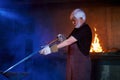 Competent aged blacksmith making sword at forge