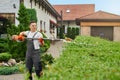 Gardener using electric trimmer for pruning bushes