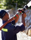 Competent in an emergency. Rearview shot of a fireman spraying water with a fire hose.