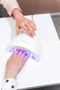 Competent manicure master turning on timer on lamp