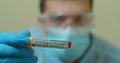 Competent medical worker in protective uniform holding test tube with blood for analysis on COVID 19 virus. Concept of