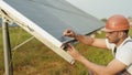 Competent technician in safety helmet and glasses measuring amperage of solar panels with multimeter. Indian man