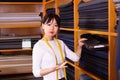 Competent young saleswoman offering various interesting cloth in textile shop