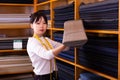 Competent young saleswoman offering various interesting cloth in textile shop