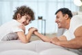 Competition. Cute latin boy and his father having fun together at home while armwrestling lying on the couch Royalty Free Stock Photo