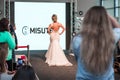 Competition of wedding stylists. A model in a white wedding dress with an open back and with a hairdo walks along the