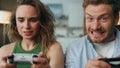 Competitive pair holding gamepads home portrait. Nervous woman losing pov video