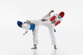 Competitive strong young men, taekwondo, karate athletes in motion, fighting, training isolated over white background