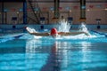 Competitive swimmer in red cap and goggles in motion, training butterfly stroke technique, swimming in pool Royalty Free Stock Photo