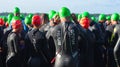 Competitors waiting to start the open water stage wearing swimming caps and wet suits at the beginning of Triathlon.