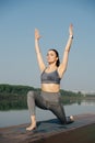 Complacent young woman doing yoga outdoors in a beautiful spot on a riverside