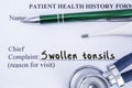 Complaint of Swollen Tonsils. Paper health history form, which is written on patient`s chief complaint of Swollen Tonsils, surroun