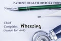 Complaint of wheezing. Paper health history form, which is written on the patient`s chief complaint of wheezing, surrounded by a s