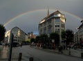 Complete rainbow surrounding a big building in a city corner