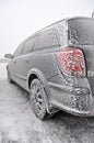 Completely frozen and snow-covered passenger car in a parking lot in winter in a thick fog