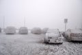 Completely frozen and snow-covered passenger car in a parking lot in winter in a thick fog