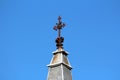 Completely rusted old gothic cross with decorative elements on top of narrow light grey metal church tower