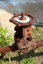Completely rusted pipeline with strong closed metal valve connected with large screws at abandoned industrial complex surrounded