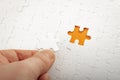 Completing final task, missing jigsaw puzzle pieces and business concept with hand holding the lacking white puzzle piece next to Royalty Free Stock Photo