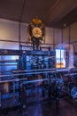 A complex clockwork mechanism with gears, wheels, and a large clock face featuring Roman numerals,
