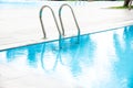 Complex swimming pool with stainless steel handrail staircase, clean water, marble edge and linear drains, luxury hotel resort Royalty Free Stock Photo