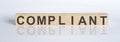 COMPLIANT word from wooden blocks on the white desk Royalty Free Stock Photo