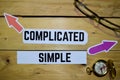 Complicated or Simple opposite direction signs with eyeglasse and compass on wooden Royalty Free Stock Photo