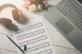 Compose music and education - paper sheet with musical notes, laptop and headphones on the artist desk Royalty Free Stock Photo