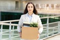 A composed professional woman carrying a cardboard box filled with office supplies and a plant Royalty Free Stock Photo