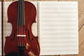 Composing for the violin. Top view of beautiful brown violin lying on sheets for music notes. Royalty Free Stock Photo