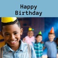 Composite of happy birthday text over happy african amercian boy in party hat at birthday party Royalty Free Stock Photo