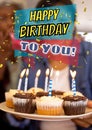 Composite of happy birthday to you text over biracial woman holding cupcakes with candles in plate